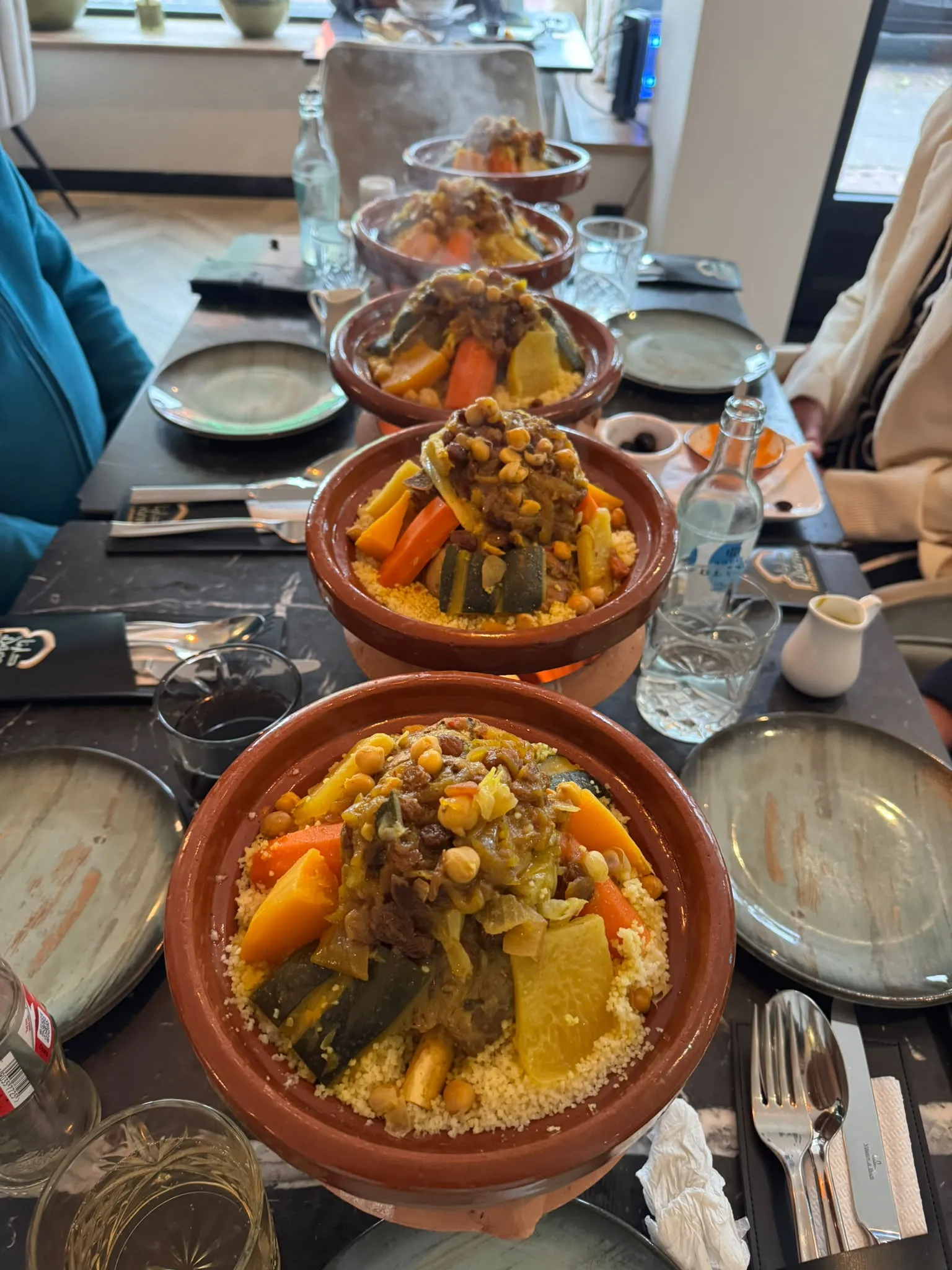 Vijf schalen couscous op een rij over een lange marmeren tafel bij Darna, klaar om uitgeserveerd te worden