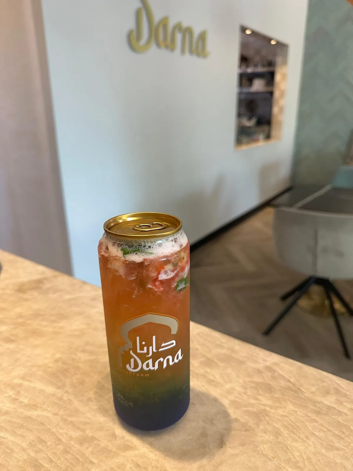 Een mojito in een Darna-blikje op de bar: oranje bovenin met verse munt en stukjes fruit, blauw onderin