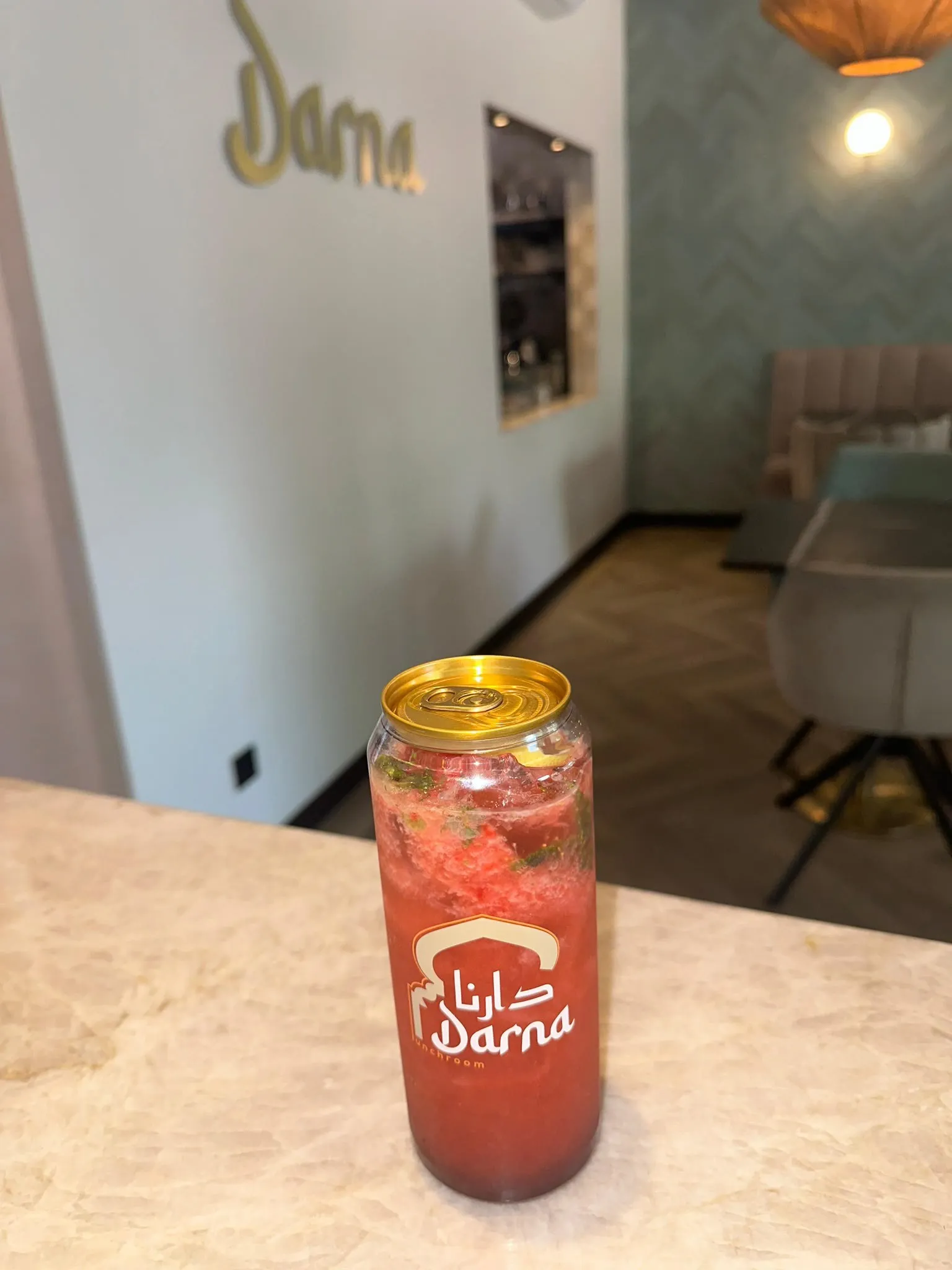 Een dieprode mojito met gestampt fruit en verse munt in een Darna-blikje op de marmeren bar