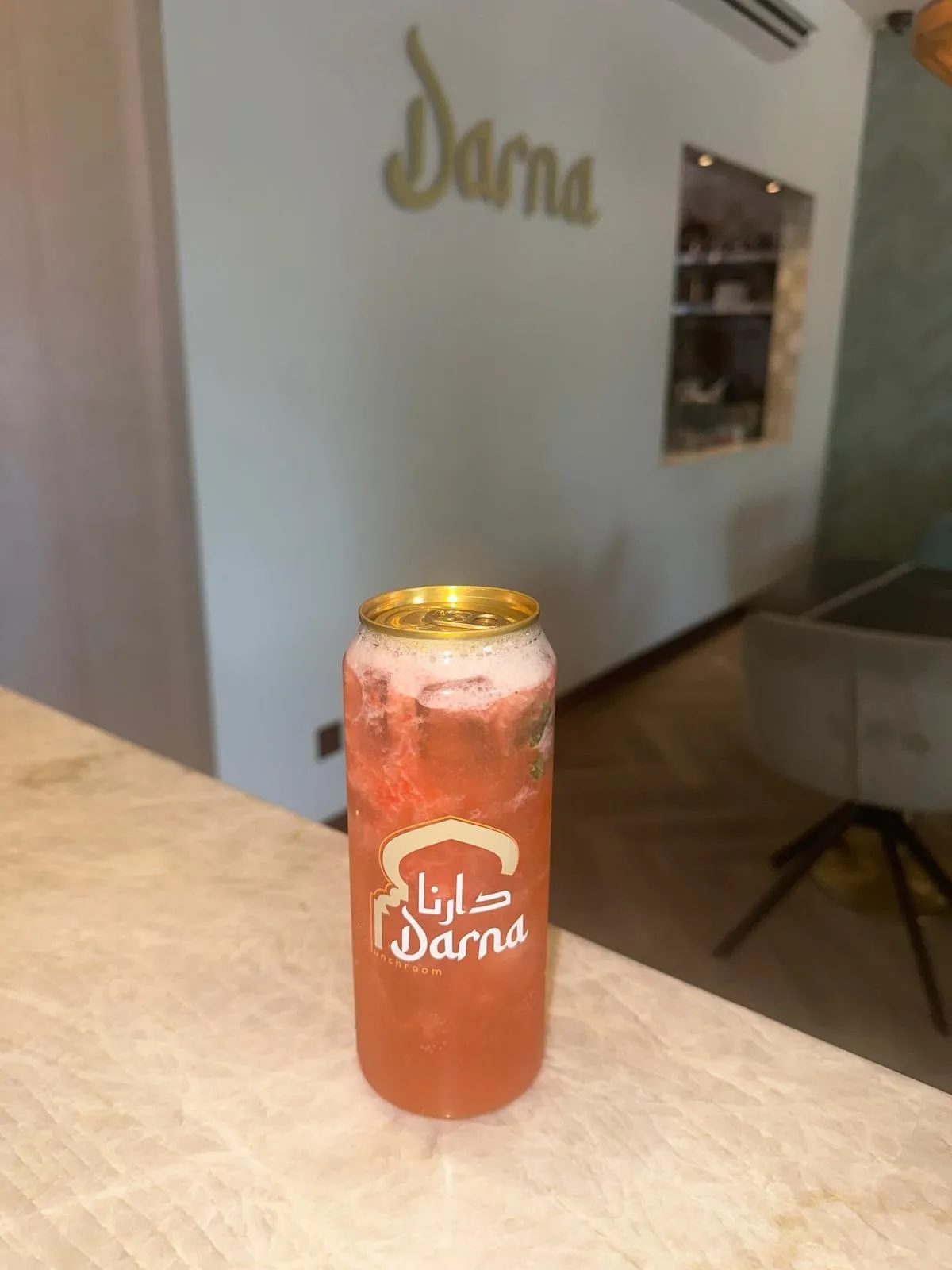 Een roze mojito met ijs en munt in een Darna-blikje op de bar, met de zaal op de achtergrond